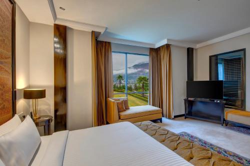 a hotel room with a bed and a television at Pearl Continental Hotel, Muzaffarabad in Muzaffarabad