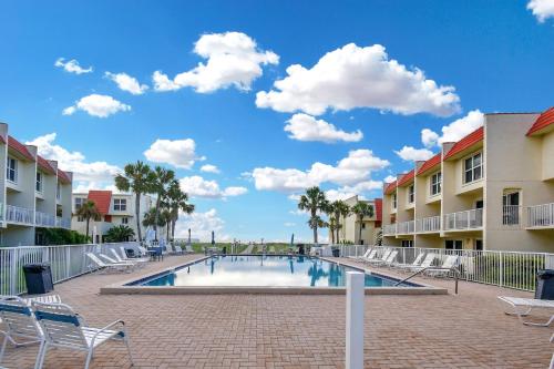 a swimming pool at a resort with chairs and condos at Ocean Front Condo With Pool Ground Floor in St. Augustine