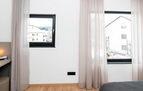 a bedroom with white curtains and a window at AmRain Ferienwohnungen in Altusried