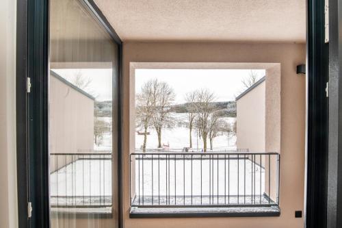 an open door to a balcony with snow on the ground at AmRain Ferienwohnungen in Altusried