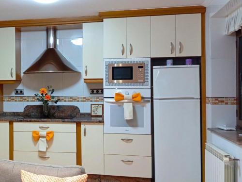 a kitchen with white cabinets and a white refrigerator at La Casa Azul 1 en Asturias in Nava