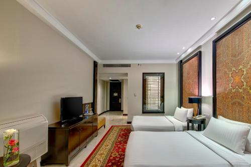 a hotel room with two beds and a flat screen tv at Pearl Continental Hotel, Muzaffarabad in Muzaffarabad