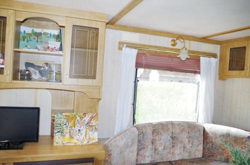 un salon avec un canapé et une fenêtre dans l'établissement Bungalow charmant à Pierrefitte-sur-Loire + jardin et BBQ, à Pierrefitte-sur-Loire