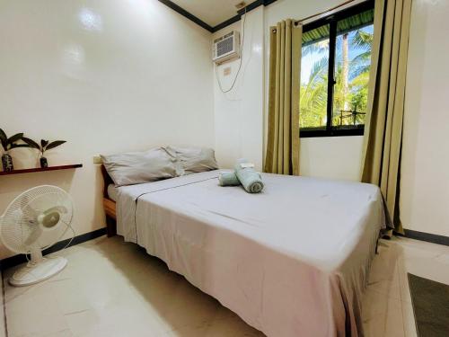 a bedroom with a bed with a fan and a window at Miraflores - Seaside Villa with private Garden in Siargao in General Luna