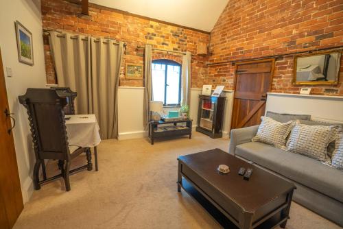 a living room with a couch and a brick wall at Hood Lane Farm - The Parlour - Self Catering Ground Floor Apartment in Arley