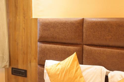a bed with a brown headboard and a yellow pillow at Hotel meet palace in Ambli Road
