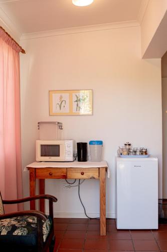 a kitchen with a table with a microwave and a refrigerator at 4 Rothman Street B&B in Graaff-Reinet