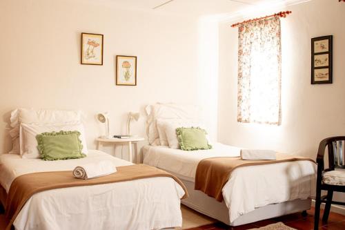 a bedroom with two beds with white sheets and green pillows at 4 Rothman Street B&B in Graaff-Reinet