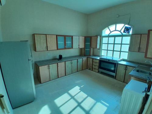 cocina vacía con ventana grande y cocina con nevera en EK Villa, en Ras al Khaimah