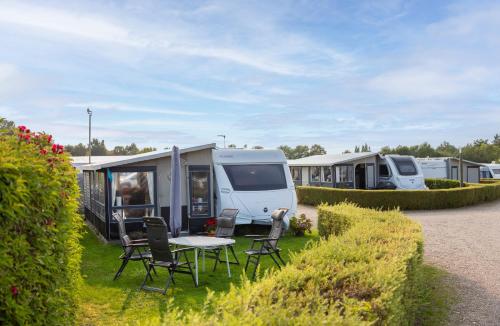 a caravan park with two rvs and a table and chairs at First Camp Holbæk Fjord in Holbæk