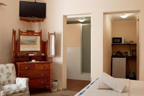 a bedroom with a dresser and a mirror and a television at 4 Rothman Street B&B in Graaff-Reinet