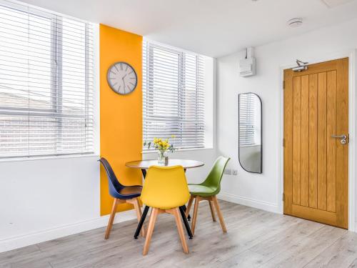 a dining room with a table and chairs and a clock at Trendy Studio Apartment in Portsmouth