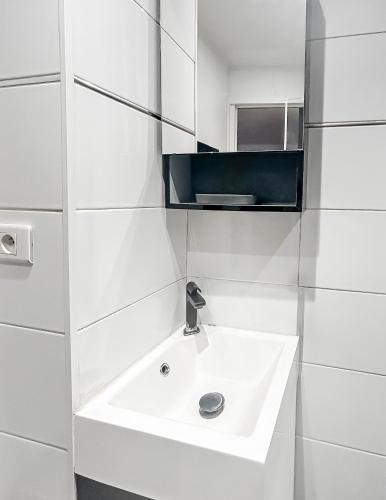 une salle de bain blanche avec un lavabo et un miroir dans l'établissement Studio Le Montebello - Vintage, WiFi et Netflix, à Fontainebleau