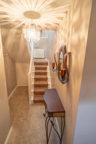 a hallway with a staircase with a chandelier and a stool at St Mary's Knocknagoran omeath in Ó Méith