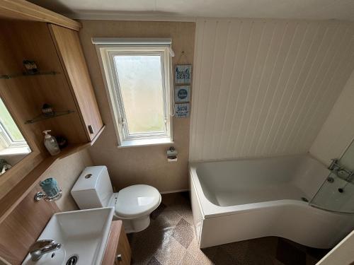 ein Badezimmer mit Badewanne, Toilette und Waschbecken in der Unterkunft Meadow Lakes 76 - sleeps 6 with a bath - Golden Palm Resort - Meadow Lakes Caravan & Lodge Hire in Chapel Saint Leonards