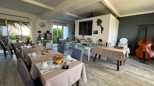 - une salle à manger avec des tables et une guitare dans l'établissement Hotel Le Goeland, à Barbâtre