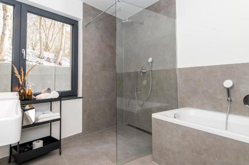 a bathroom with a tub and a glass shower at AmRain Ferienwohnungen in Altusried