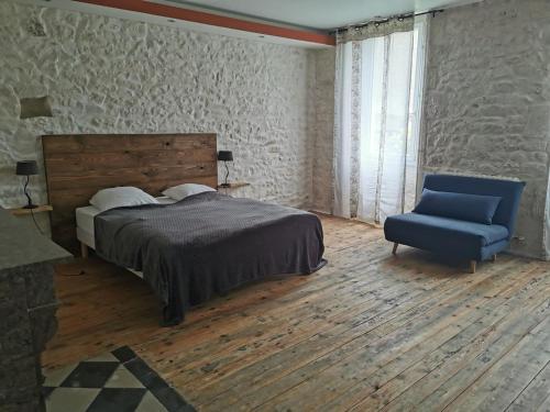 a bedroom with a bed and a blue chair at Le puech des Amandiers in Villeneuve-sur-Vère