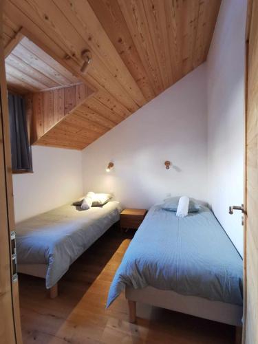 deux lits dans une chambre avec plafonds en bois dans l'établissement Duplex rénové au pied des pistes, au Monêtier-les-Bains