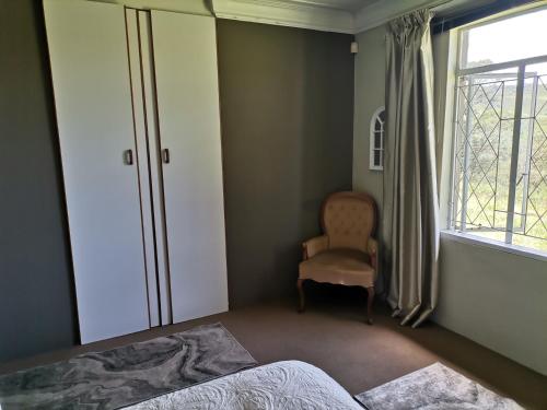 a bedroom with a bed and a chair and a window at Green Hills Farm House in Drummond