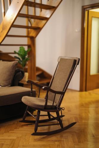 a rocking chair in a living room with a staircase at CASA NATURA - charming chalet with hot tub in Tuk Vojni