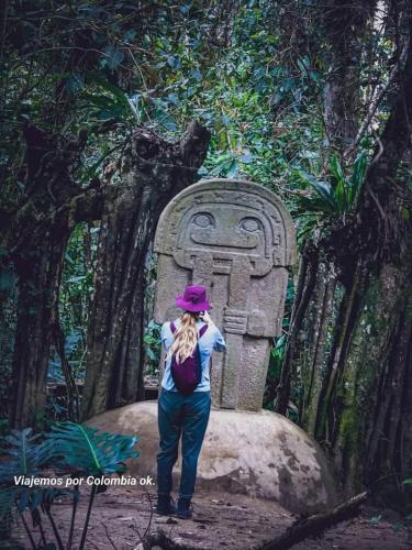a woman standing in front of a stone statue at Botón de oro hostal in San Agustín