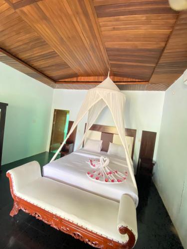 a bedroom with a white bed with a wooden ceiling at Amoryg Resort and Dive Raja Ampat in Pulau Mansuar