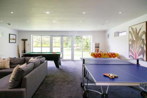 a living room with a ping pong table in it at Stunning 5BR Home with Pool - 5 min to Beach in West Wittering