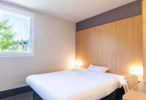 a bedroom with a large white bed and a window at B&B HOTEL Alès - Pôle Mécanique in Saint-Martin-de-Valgalgues