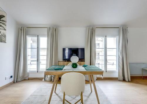 une salle à manger avec une table et deux fenêtres dans l'établissement Sur un nuage - Calme & Rénové - Odéon, à Paris