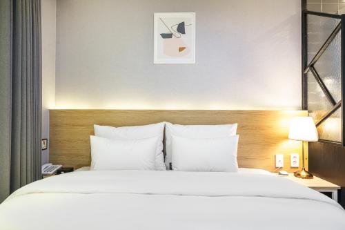 a bedroom with a large bed with white sheets and pillows at Brown Dot Hotel Angang in Gyeongju