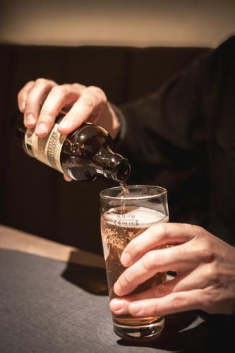 a person pouring a bottle of beer into a glass at Haunold Homes in San Candido