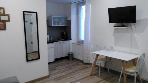 Il comprend une petite cuisine avec une table et une télévision murale. dans l'établissement RDC cosy en centre ville, à Narbonne