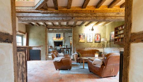 a living room with leather chairs and a table at Gîte de charme en rez de jardin in Berdʼhuis