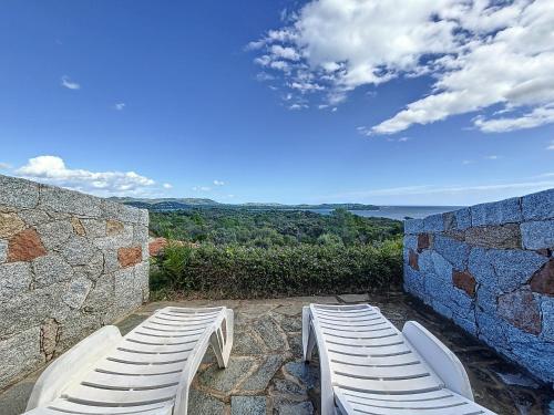 two white chairs sitting next to a stone wall at Résidence Les Pavillons du Belvédère in Porto-Vecchio