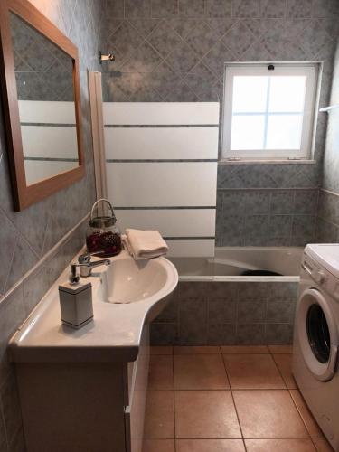 a bathroom with a sink and a washing machine at Quinta Das Palmeiras in Quarteira