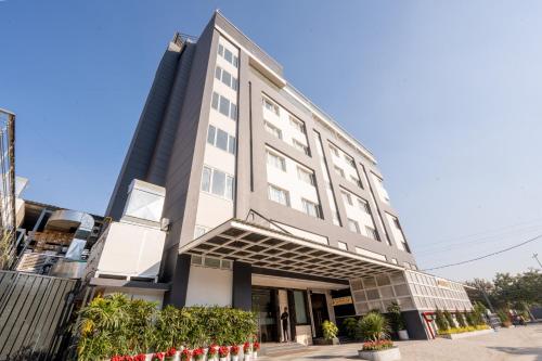 a tall white building with plants in front of it at Ramee Tarang Hotel Indore in Indore