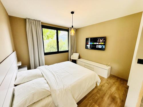 une chambre avec un lit et une télévision au mur dans l'établissement L'ancienne Étude - Superbe vue - Piscine chauffée, à Buis-les-Baronnies