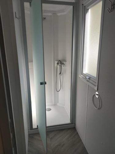 La salle de bains est pourvue d'une douche en verre avec un miroir. dans l'établissement MOBIL HOME la STEPHANOISE, à Valras-Plage