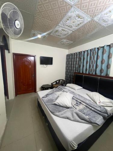 a bedroom with a bed and a ceiling with a fan at Mussiaree Hotel in Murree