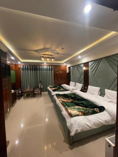 two large beds in a room with a table at Mussiaree Hotel in Murree