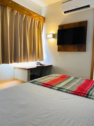 a bedroom with a bed and a desk and a television at Meu Hotel Boituva in Boituva