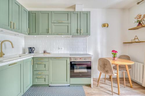 une cuisine avec des placards verts et une table en bois dans l'établissement Apartment in Paris 17th District, à Paris