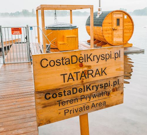a sign on a dock next to a boat at Costa del Kryspi Całoroczne Domy na Wodzie in Cholerzyn