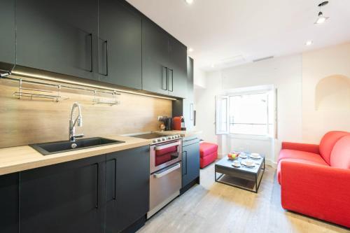 une cuisine avec des armoires noires et un canapé rouge dans l'établissement 1-Br Apartment with Air Conditioning Near La Croisette, à Cannes