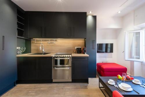 une cuisine avec des armoires noires et une table rouge dans l'établissement 1-Br Apartment with Air Conditioning Near La Croisette, à Cannes