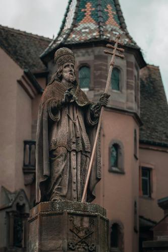 a statue of a man holding a wand and a stick at Gite Traditionnel au Centre Historique d'Éguisheim in Eguisheim