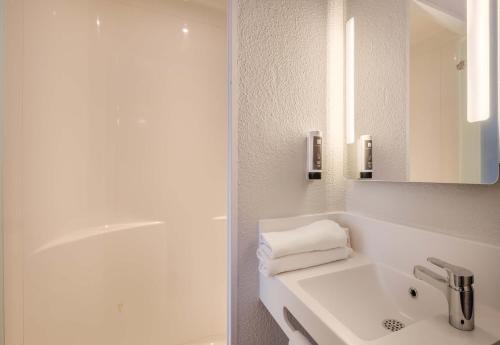 une salle de bain blanche avec un lavabo et une douche dans l'établissement B&B HOTEL Antibes Sophia Antipolis, à Biot