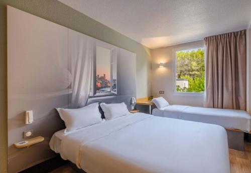 une chambre d'hôtel avec deux lits et une fenêtre dans l'établissement B&B HOTEL Antibes Sophia Antipolis, à Biot