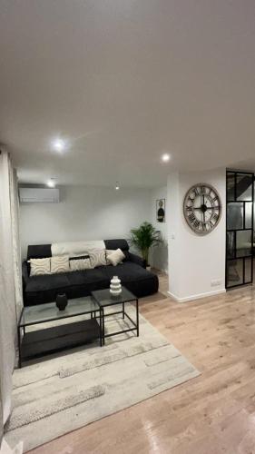 a living room with a black couch and a clock at Maison cozy proche centre ville in Orvault